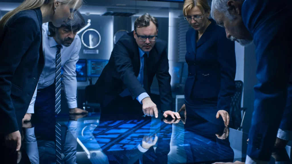 A team of professionals analyses data on a digital table.